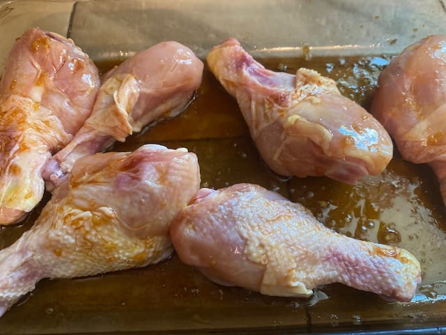 Soy sauce, oil and ginger in a pan with chicken legs